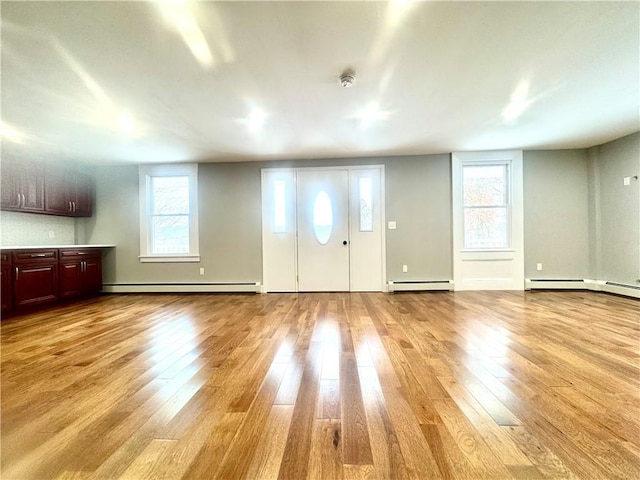 entryway featuring light wood-type flooring, a healthy amount of sunlight, and baseboard heating