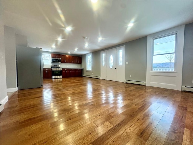 unfurnished living room with hardwood / wood-style flooring and a baseboard heating unit