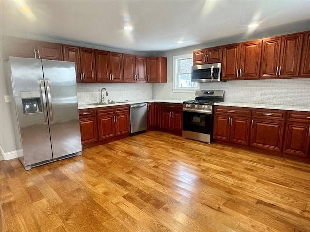 kitchen with decorative backsplash, sink, light hardwood / wood-style flooring, and stainless steel appliances