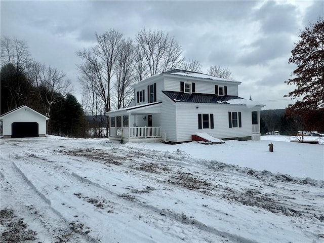 snow covered back of property with a garage, a porch, and an outdoor structure