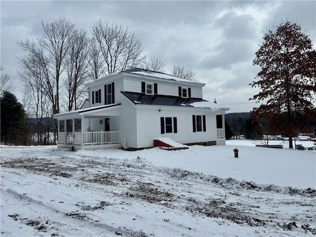 snow covered back of property with covered porch