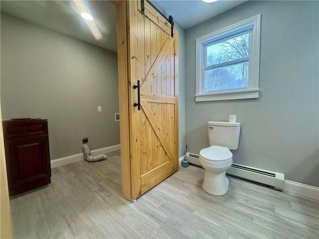 bathroom featuring baseboard heating, hardwood / wood-style floors, and toilet