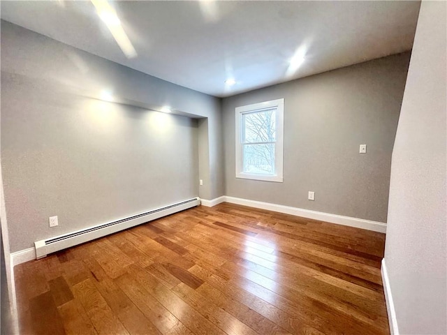 spare room with hardwood / wood-style flooring and a baseboard heating unit