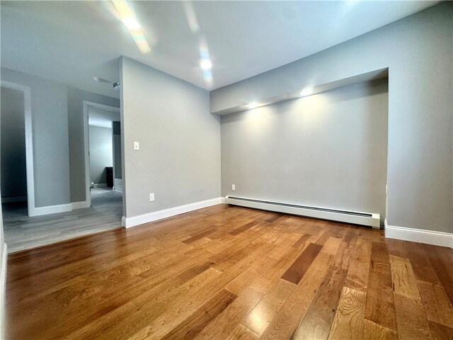 unfurnished room with a baseboard radiator and hardwood / wood-style floors