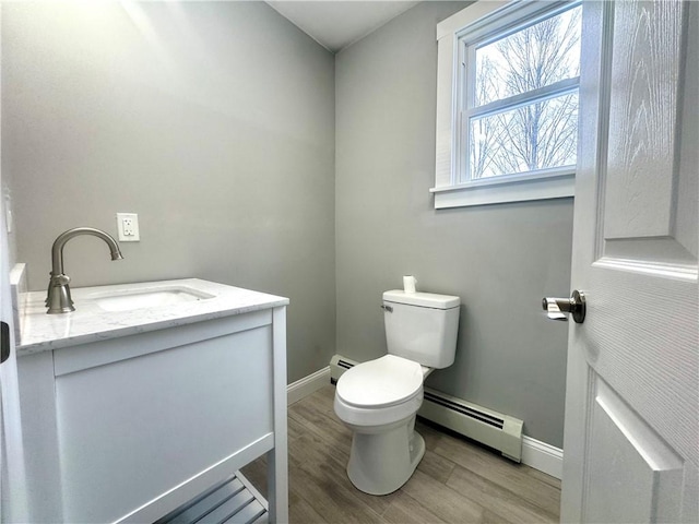 bathroom featuring baseboard heating, hardwood / wood-style floors, toilet, and vanity