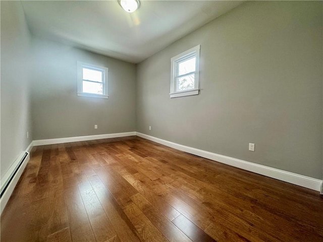 empty room featuring baseboard heating and wood-type flooring