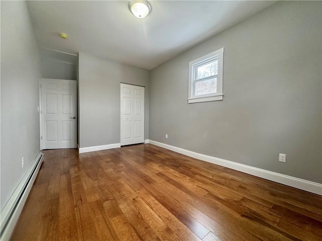 unfurnished bedroom featuring baseboard heating and hardwood / wood-style floors