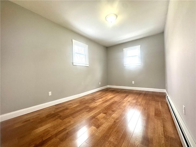 unfurnished room featuring baseboard heating and wood-type flooring