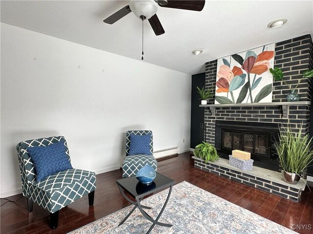 living area featuring ceiling fan, baseboard heating, dark hardwood / wood-style flooring, and a fireplace