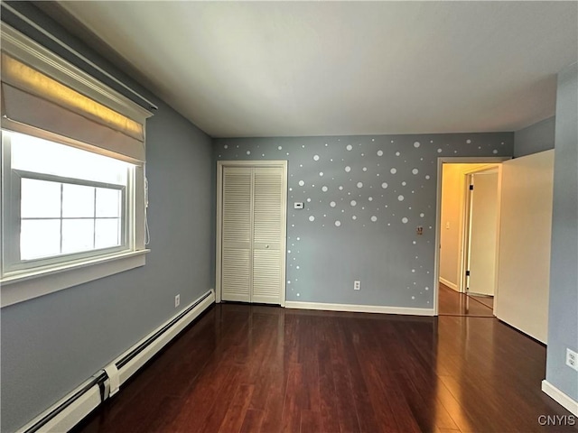 spare room featuring a baseboard heating unit and hardwood / wood-style floors