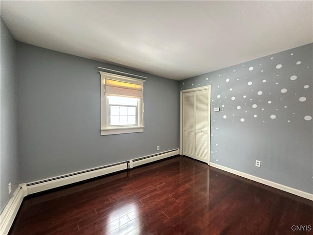 unfurnished bedroom with a baseboard heating unit, a closet, and dark hardwood / wood-style flooring