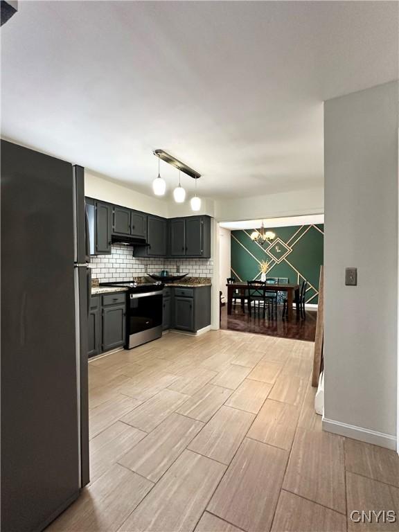 kitchen with gray cabinets, appliances with stainless steel finishes, tasteful backsplash, and a notable chandelier