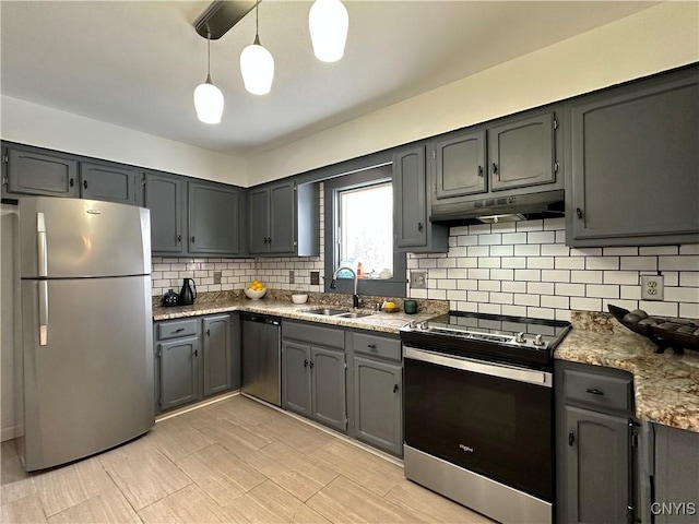 kitchen with light stone countertops, appliances with stainless steel finishes, tasteful backsplash, sink, and hanging light fixtures