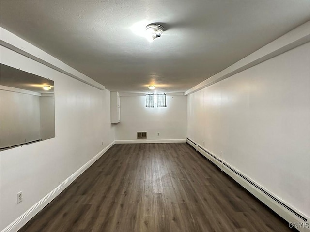 basement with dark wood-type flooring and baseboard heating