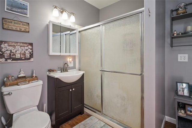 bathroom with toilet, vanity, a shower with door, and hardwood / wood-style flooring