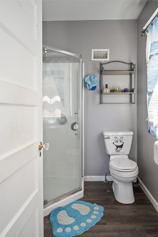 bathroom featuring hardwood / wood-style flooring, toilet, and a shower with door