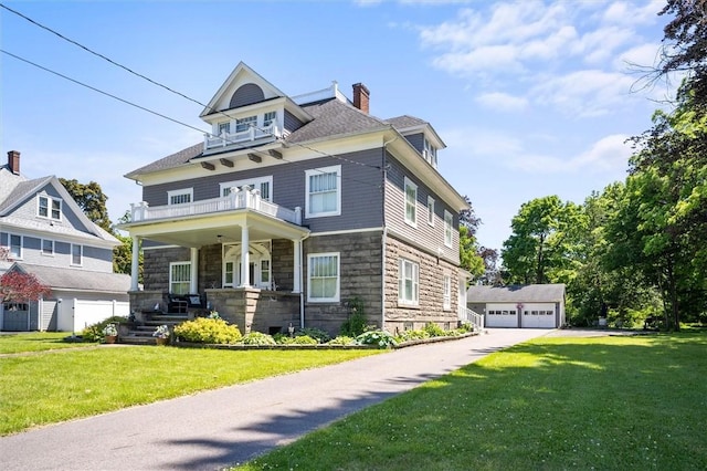 victorian-style house with a front yard, a balcony, covered porch, an outdoor structure, and a garage