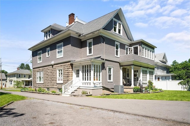 view of front of property with a front lawn and central air condition unit