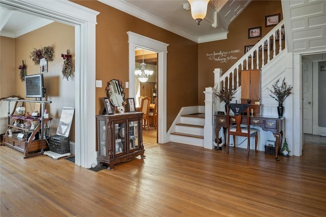 foyer with ornamental molding, hardwood / wood-style flooring, and a notable chandelier