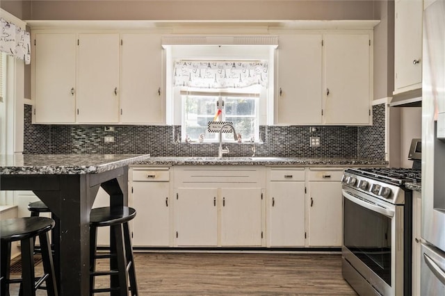 kitchen with light stone counters, white cabinets, backsplash, and stainless steel range with gas cooktop