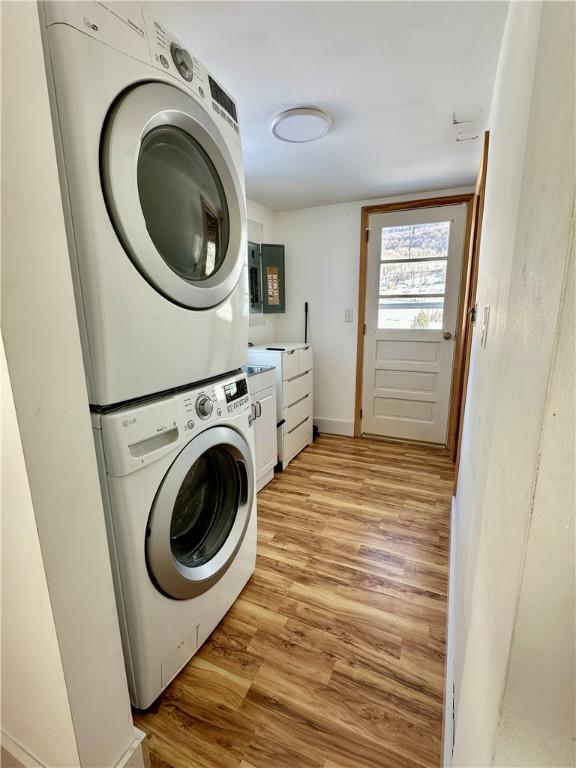 clothes washing area featuring stacked washer and dryer and light hardwood / wood-style flooring