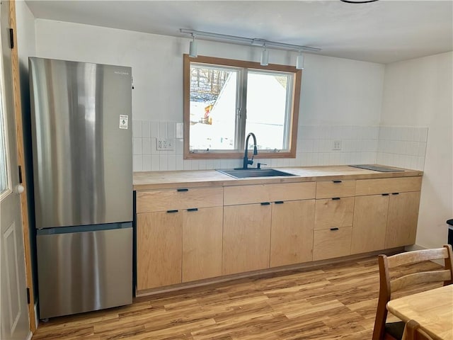 kitchen featuring tasteful backsplash, sink, stainless steel refrigerator, and light brown cabinetry