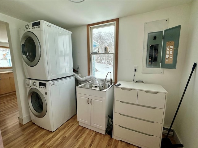 washroom with cabinets, stacked washer and dryer, sink, light wood-type flooring, and electric panel