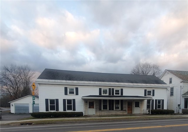 view of front of home featuring a garage, an outdoor structure, and covered porch