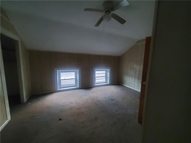 additional living space with ceiling fan, wood walls, carpet, and lofted ceiling