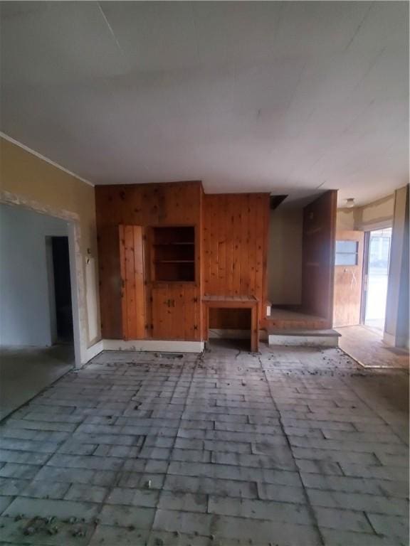 unfurnished living room featuring wood walls