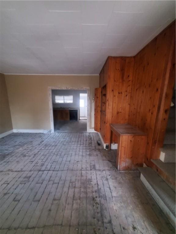 unfurnished living room featuring wood-type flooring and wooden walls