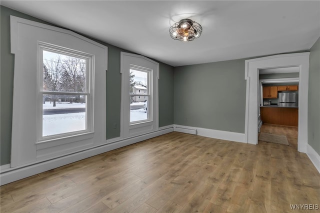 unfurnished dining area featuring lofted ceiling, baseboard heating, and light hardwood / wood-style floors