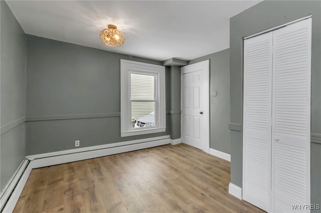 unfurnished bedroom featuring light hardwood / wood-style floors and baseboard heating