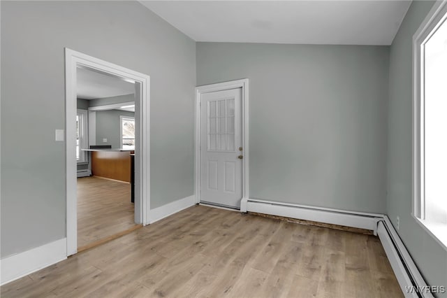 spare room featuring a baseboard heating unit and light wood-type flooring