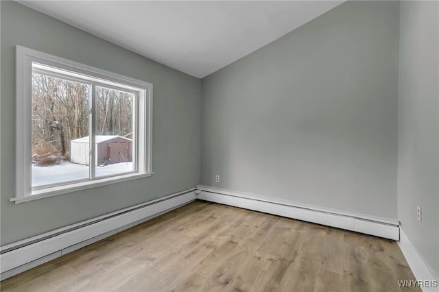 empty room with light wood-type flooring and a baseboard heating unit