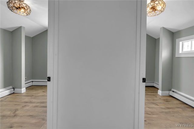 hall featuring a baseboard heating unit and light hardwood / wood-style flooring