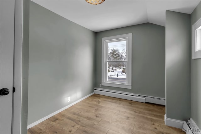 unfurnished room with a baseboard heating unit, light hardwood / wood-style flooring, and vaulted ceiling