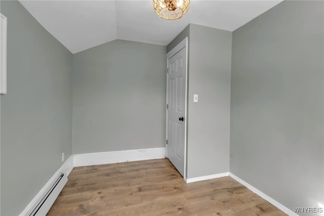 interior space with a baseboard heating unit, lofted ceiling, and light hardwood / wood-style flooring