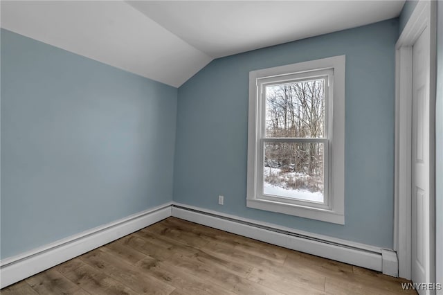 additional living space featuring vaulted ceiling, a baseboard heating unit, and light wood-type flooring