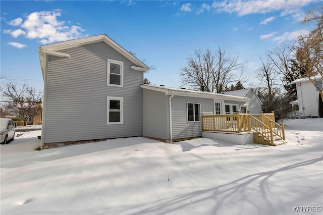 snow covered rear of property with a deck