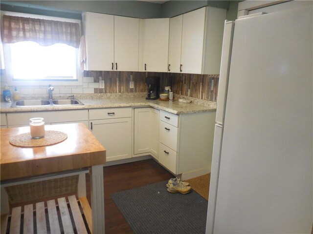 kitchen with white fridge, white cabinetry, tasteful backsplash, and sink