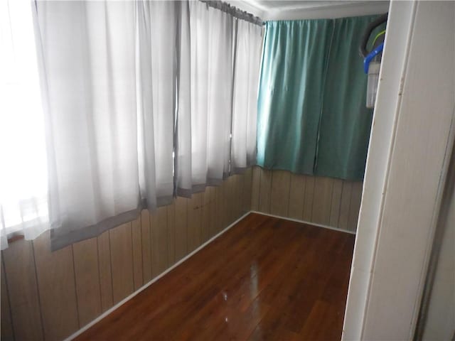 spare room featuring dark hardwood / wood-style flooring and wood walls