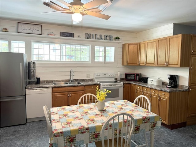 kitchen featuring ceiling fan, sink, wooden walls, and white appliances