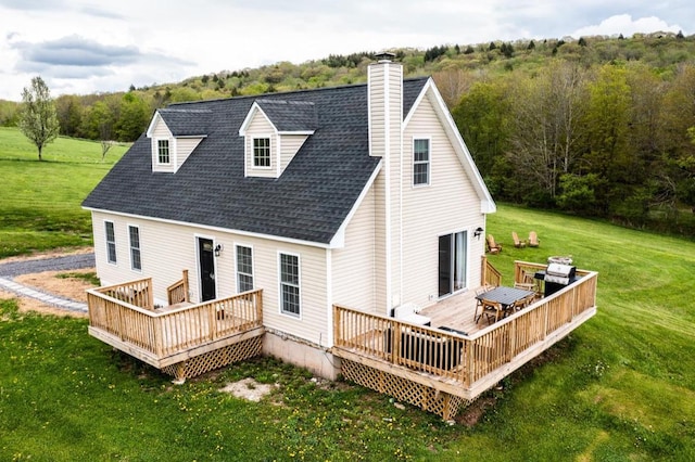 rear view of property featuring a wooden deck and a lawn