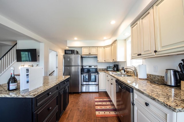 kitchen with stainless steel appliances, dark wood-type flooring, white cabinets, light stone counters, and sink