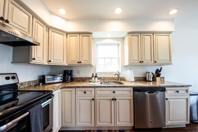 kitchen featuring sink, appliances with stainless steel finishes, cream cabinets, and dark stone countertops