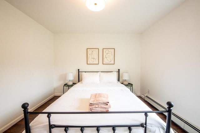 bedroom featuring a baseboard heating unit and dark hardwood / wood-style floors