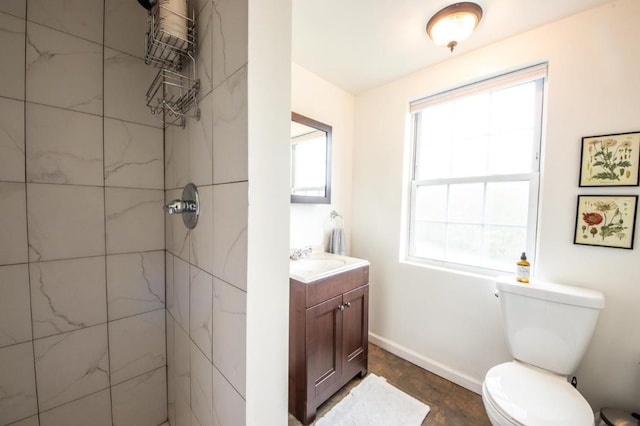 bathroom with plenty of natural light, tiled shower, vanity, and toilet