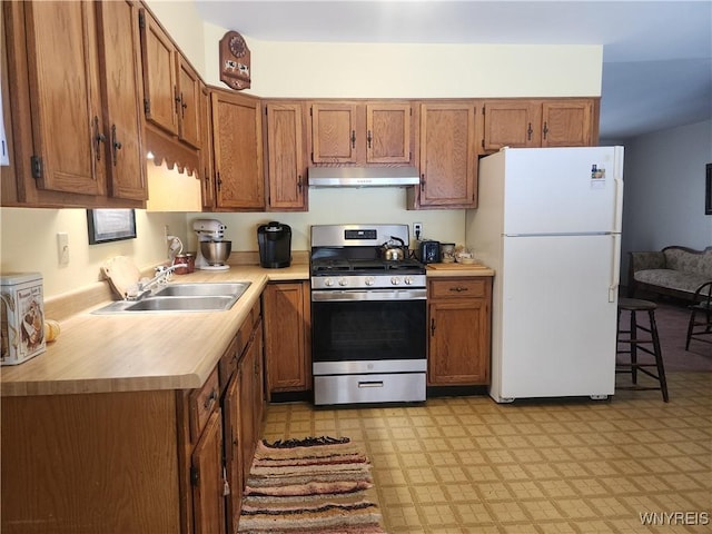 kitchen with sink, white refrigerator, and stainless steel range with gas stovetop