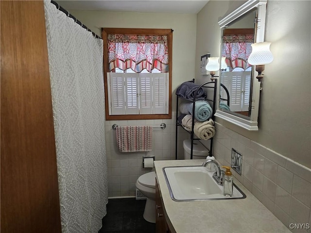 bathroom with toilet, tile walls, and vanity